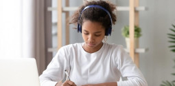 teenage girl wearing headphones doing homework